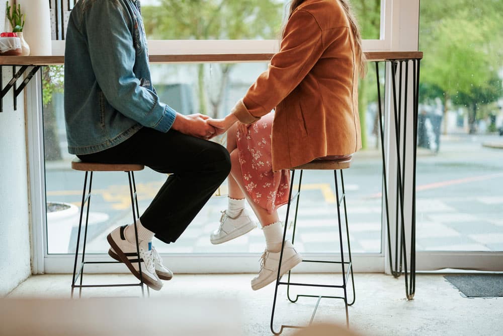 A young couple holding hands in a café, symbolizing the challenges and strategies for navigating romantic relationships while living with ADHD.