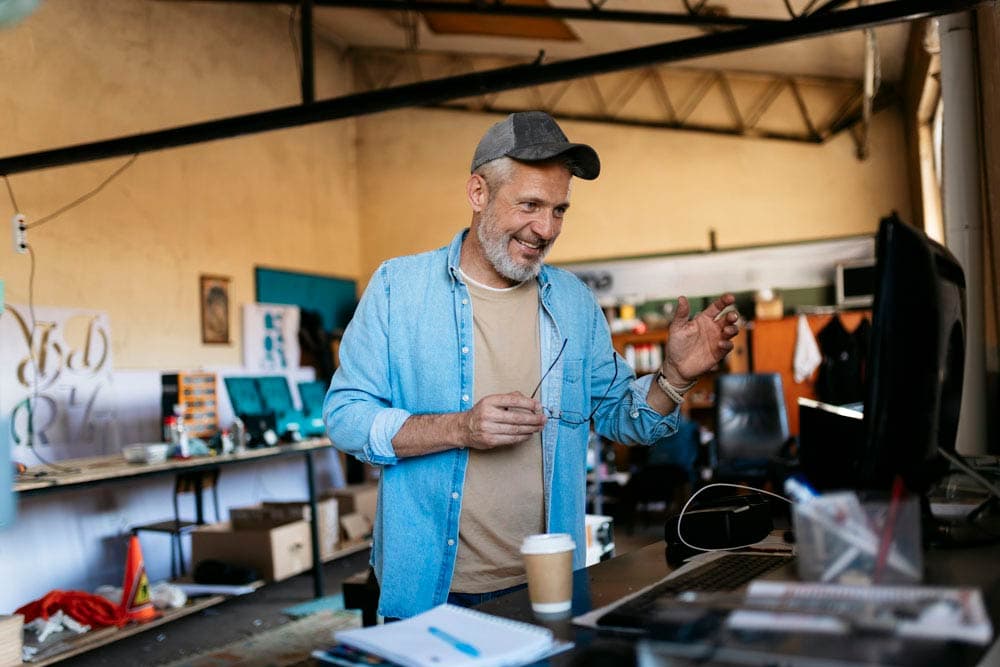 Smiling man standing in a creative workspace, symbolizing focus and productivity strategies for managing ADHD at work.