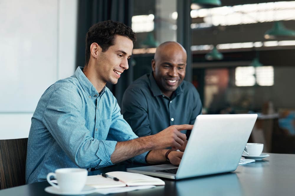 Two professionals conversing in front of a laptop, symbolizing the importance of evidence-based understanding in debunking ADHD misconceptions.