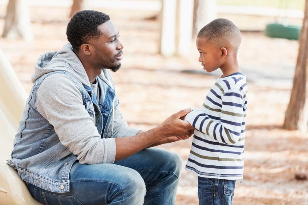 A father kneels to talk compassionately with his young son about behavior, showing ADHD parenting strategies that balance structure and empathy.