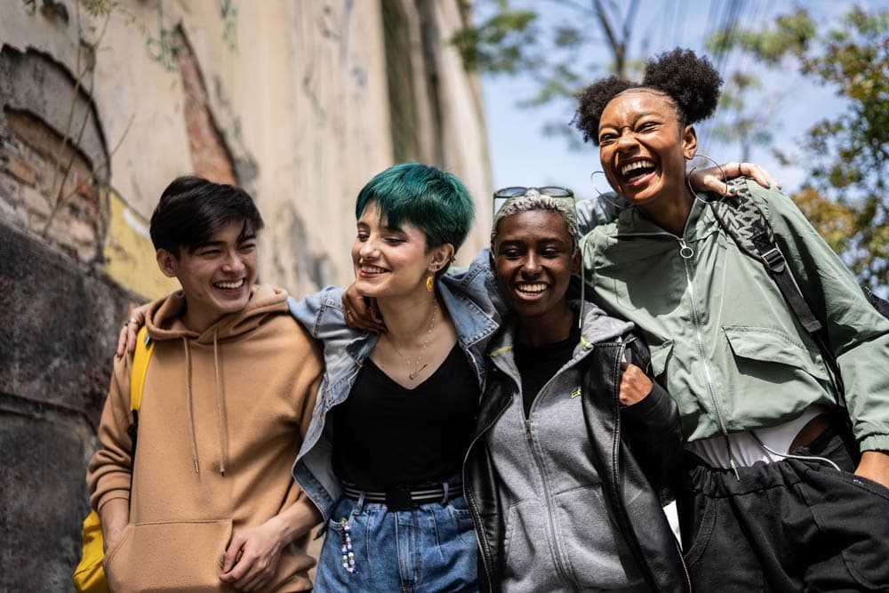 Diverse group of young adults laughing together outdoors, symbolizing friendships and support networks for ADHD students.