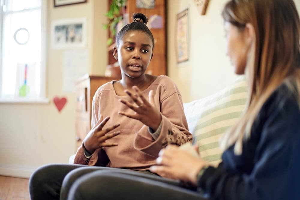 A teenage girl talks with an adult during a supportive conversation, illustrating how structured guidance helps teens with ADHD strengthen communication skills and confidence.