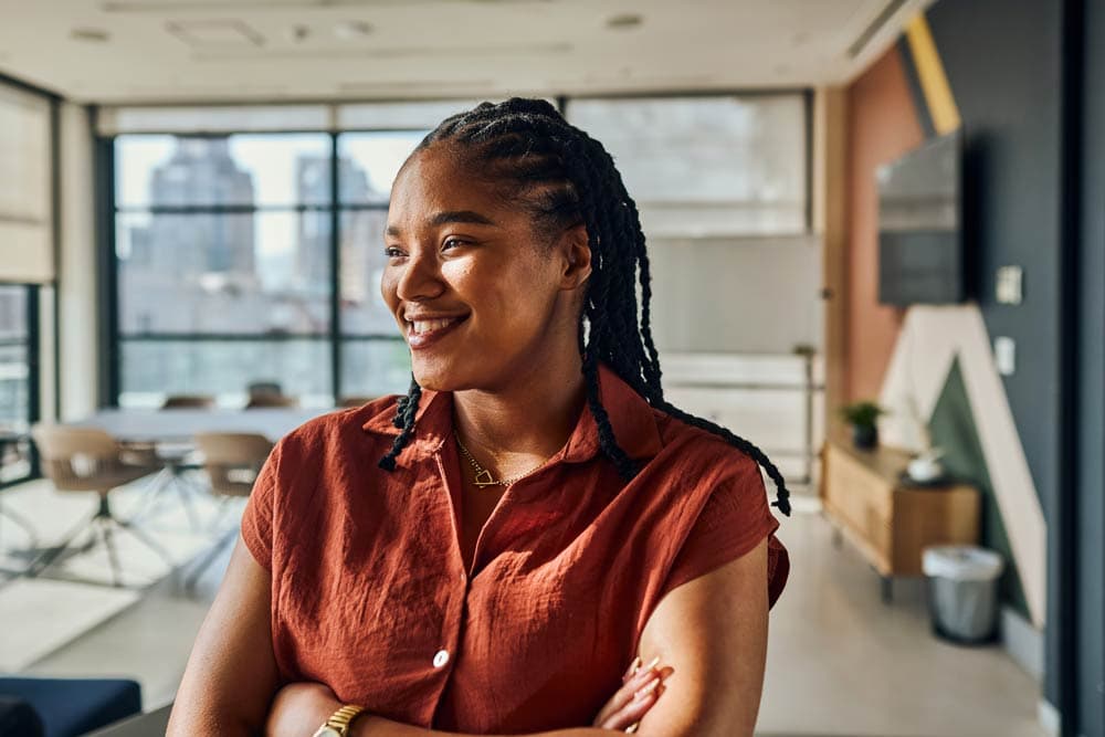 A confident woman smiling in a modern office, symbolizing self-advocacy and building confidence in women living with ADHD.