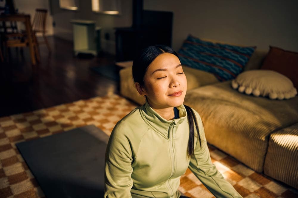 Teen practicing mindfulness meditation indoors with eyes closed, representing calm focus and emotional regulation strategies for ADHD.