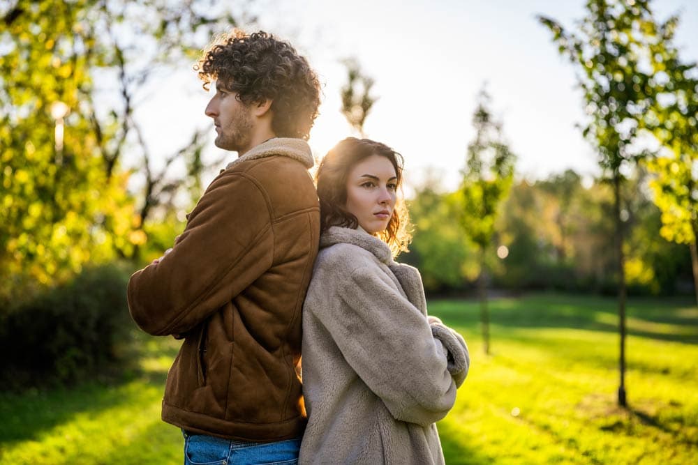 Man and woman standing back to back outdoors, symbolizing gender differences in ADHD experiences and diagnosis.