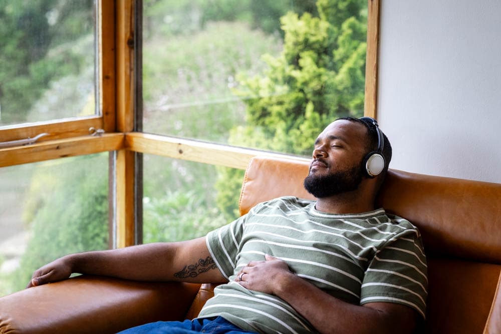 Man sitting in a chair with headphones, practicing mindfulness to improve focus and reduce stress associated with ADHD.