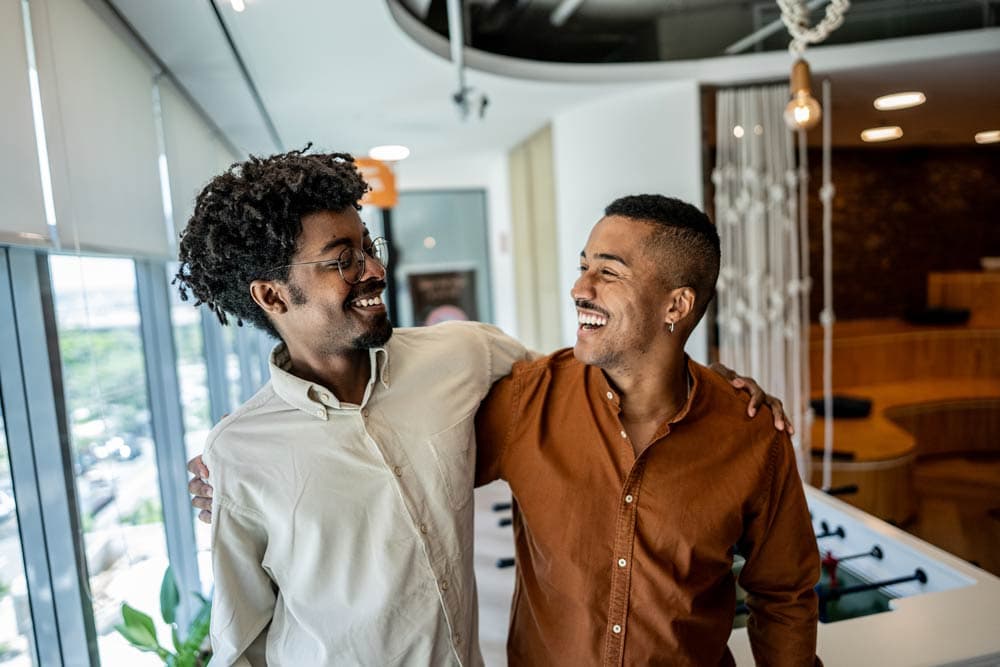 Two friends smiling and walking together indoors, representing the importance of maintaining supportive friendships despite ADHD-related forgetfulness.