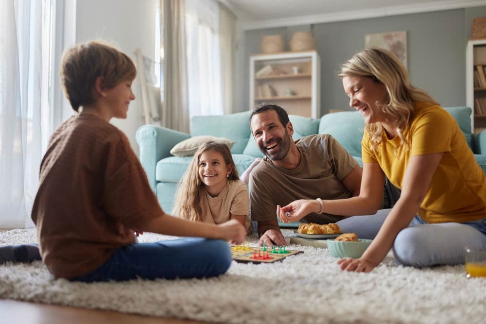 Happy family playing a board game together, representing ADHD-friendly co-parenting strategies and shared responsibilities.