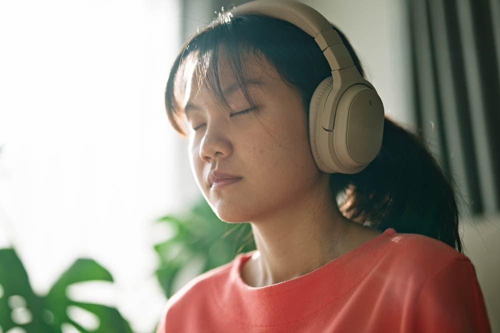 Teen girl wearing headphones with eyes closed, practicing a mindfulness exercise to improve focus and emotional regulation for ADHD management.
