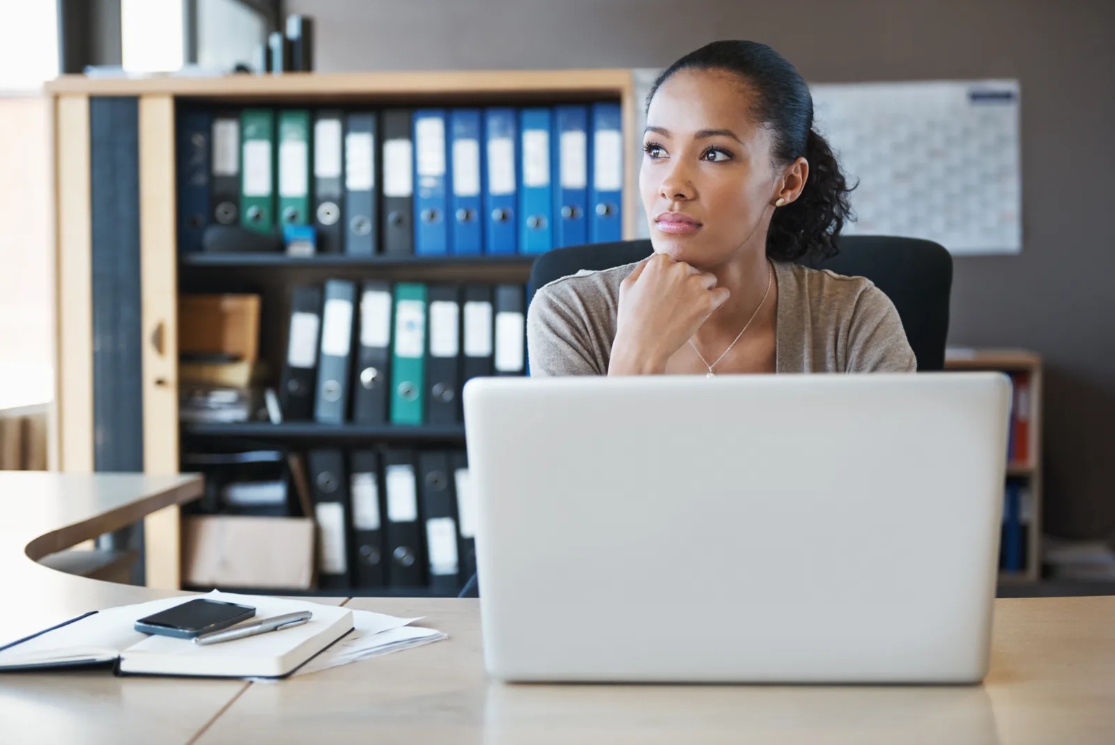 Thoughtful adult reflecting on possible ADHD symptoms while working at a cluttered desk
