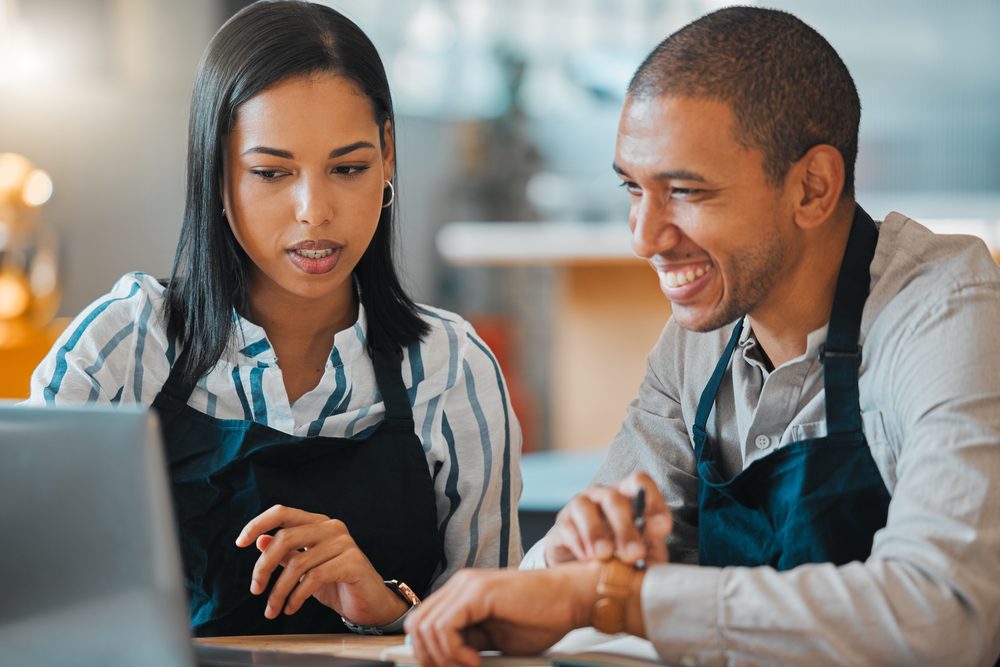 Manager and employee talking across a small table in a glass-walled meeting room