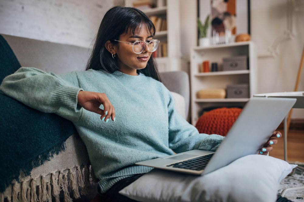 Young university student with ADHD studying on a laptop at home, using chunking strategies to break study sessions into smaller, manageable parts.