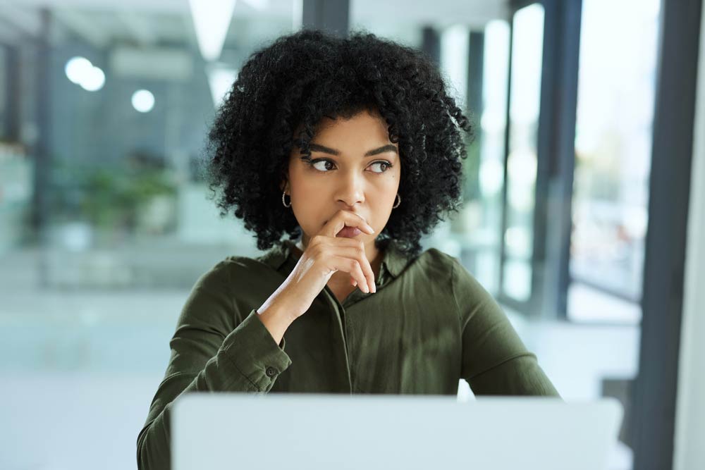 Thoughtful woman sitting at a desk, struggling with decision-making and organization, illustrating how ADHD impulsivity affects daily life.