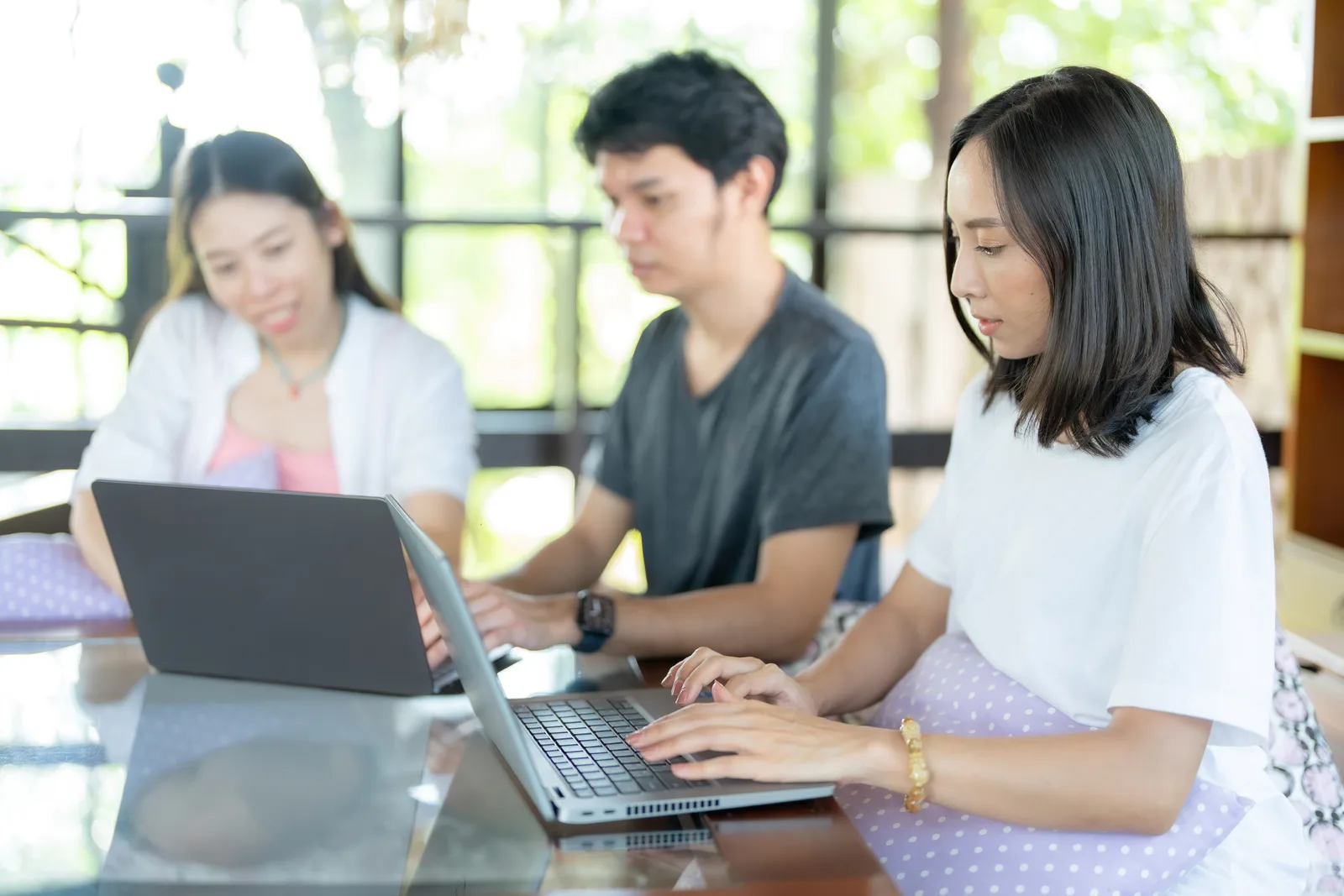 An international university student with a backpack studies at a table in a bright campus library, weighing her options for an ADHD assessment in Canada.