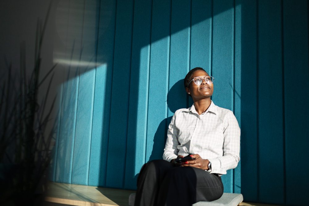 Young adult at a kitchen table with unopened envelopes and a phone showing reminders