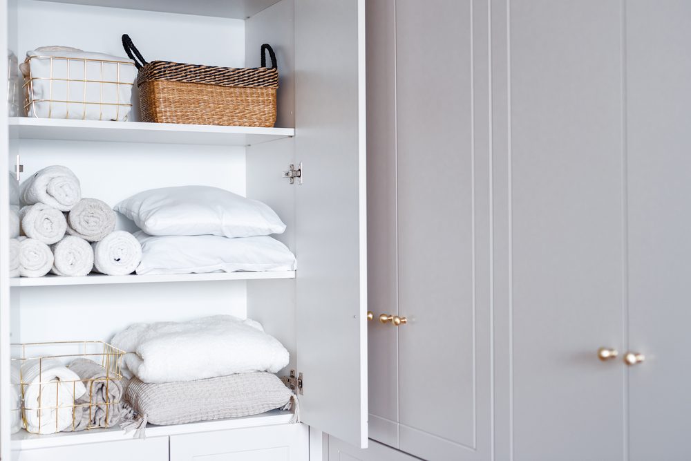 Laundry basket of clean clothes on a bed next to open dresser drawers