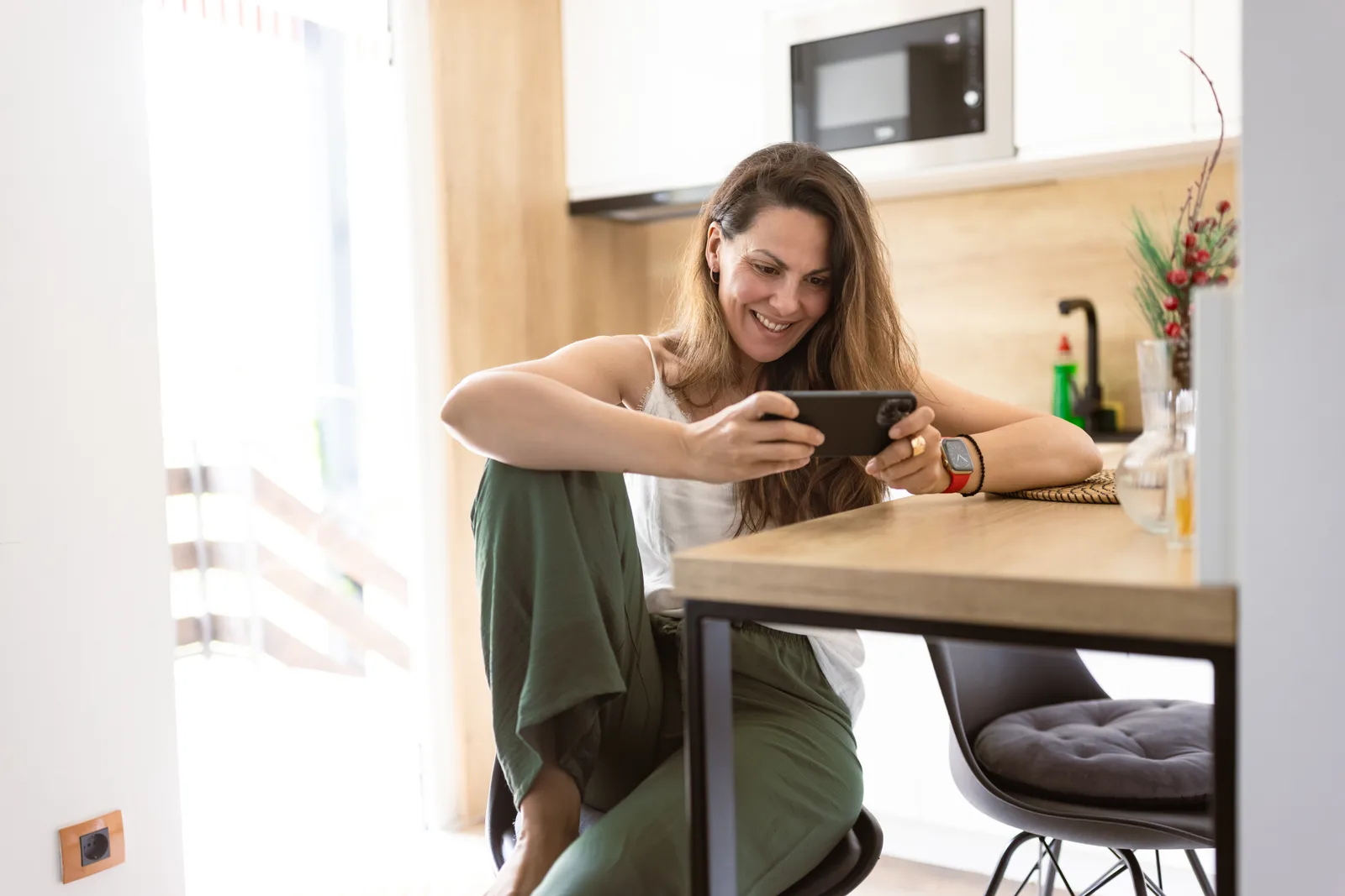 Two friends talking over coffee at a kitchen counter in bright natural daylight.
