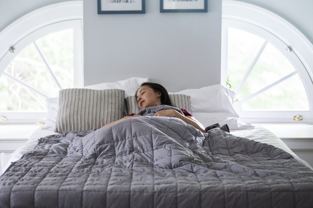 Woman at a desk staring at a blank document on her laptop, pen untouched