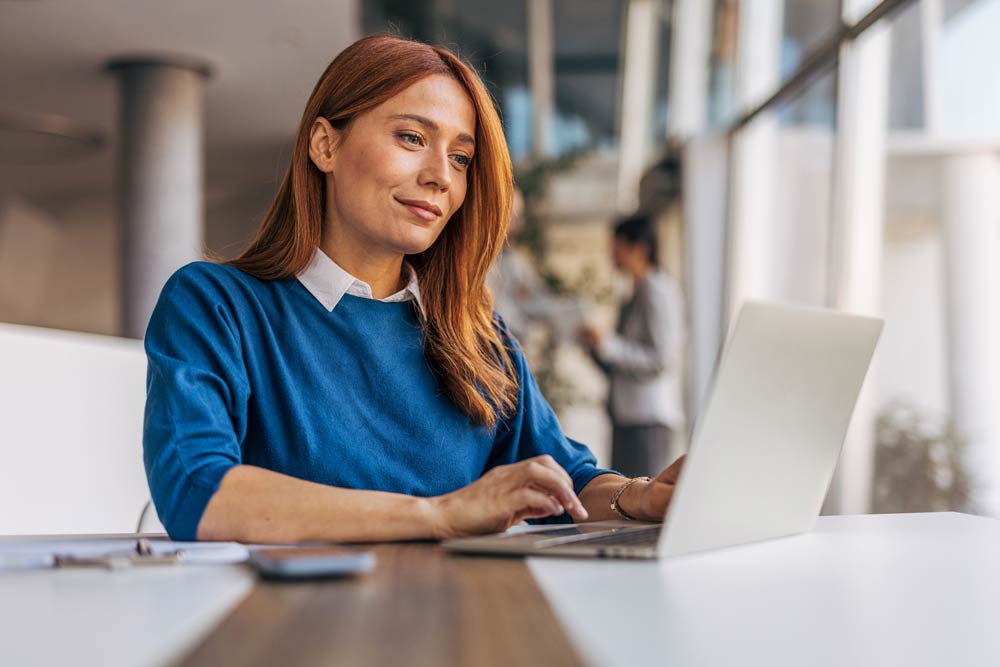 A professional woman working on a laptop in an office, representing the challenges and strategies women with ADHD use to balance careers and symptoms.