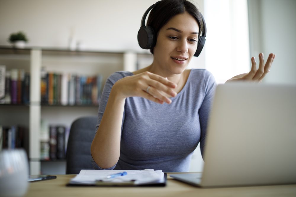 Woman working at a laptop on a video call with another person also working