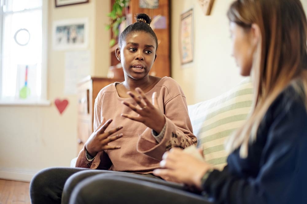 A teenage girl talks with an adult during a supportive conversation, illustrating how structured guidance helps teens with ADHD strengthen communication skills and confidence.