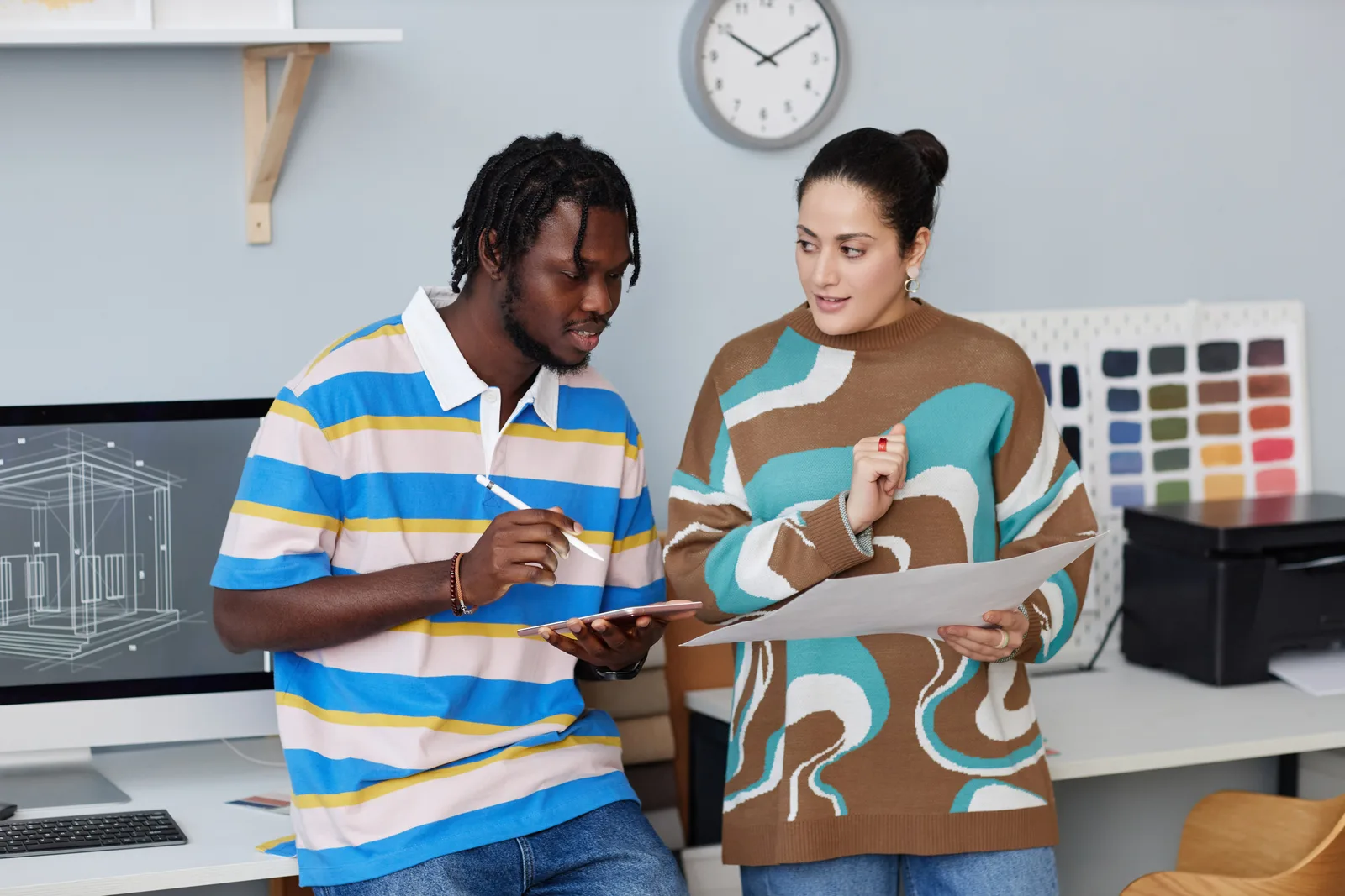 Two people review printed checklists together across a table in a bright, modern office, comparing what quality ADHD care in Canada should include.