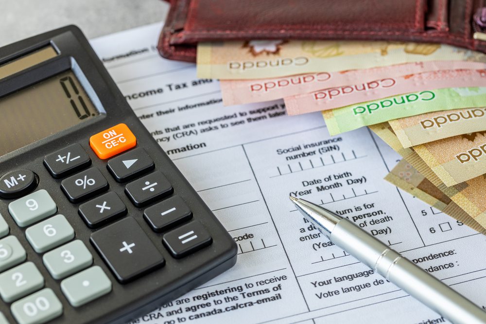Adult at a kitchen table reading a printed government tax form with a pen