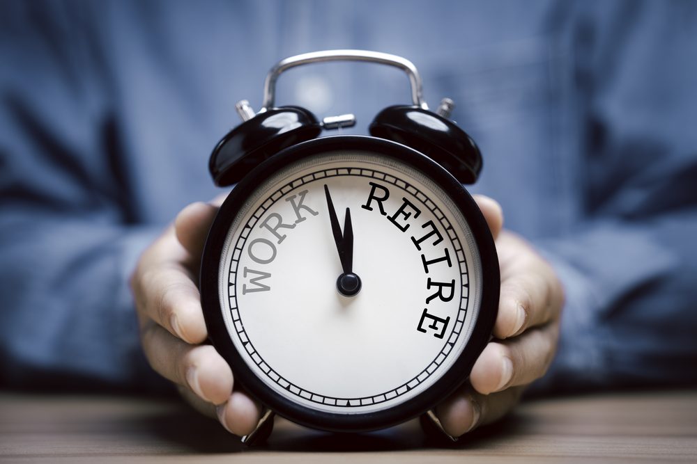 Person adjusting an alarm clock on a bedside table in early morning light