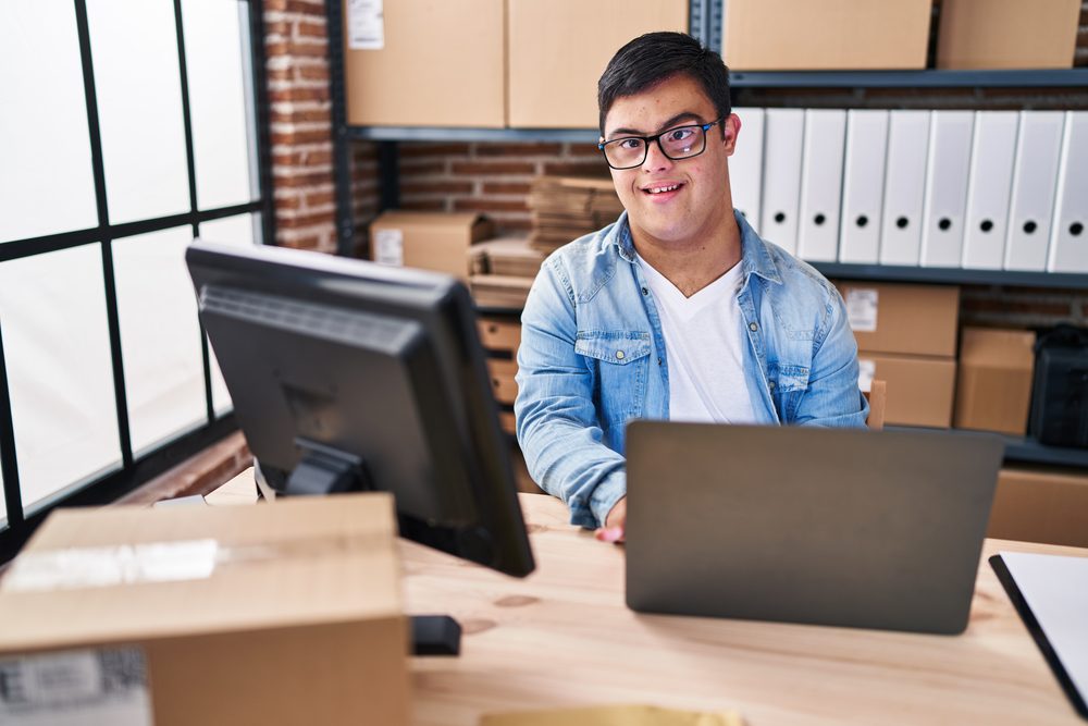 Man at a home desk entering appointments into a calendar on his laptop