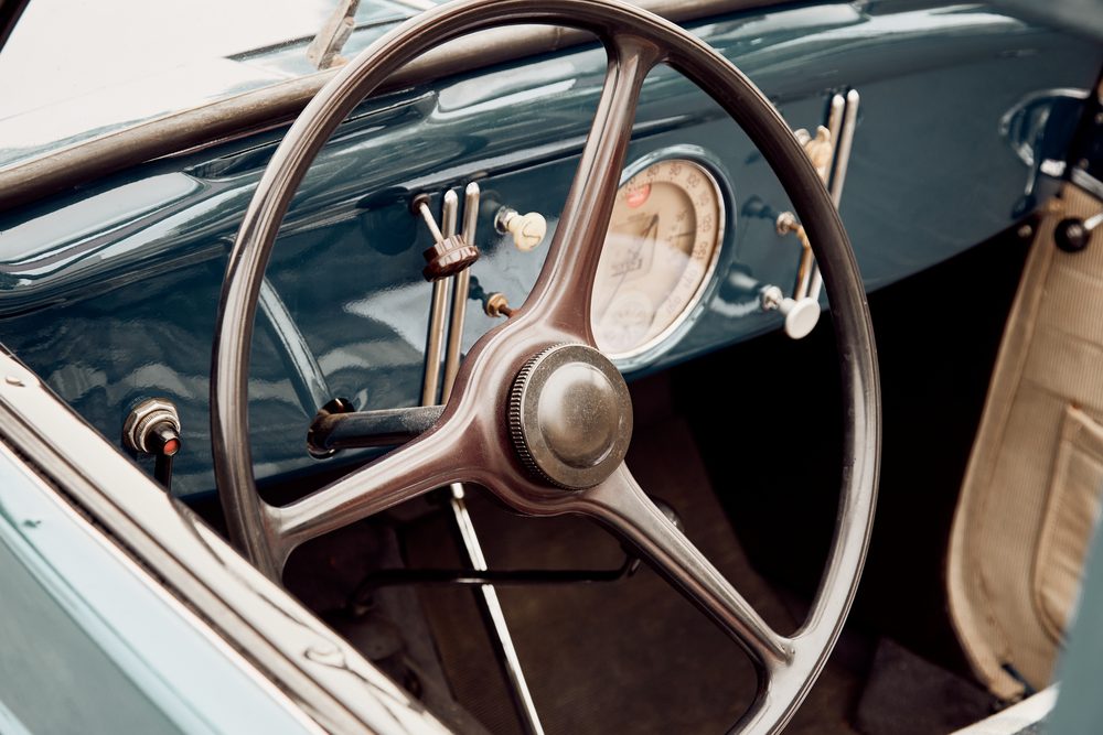 Driver's hands on a steering wheel with a phone mounted on the dashboard