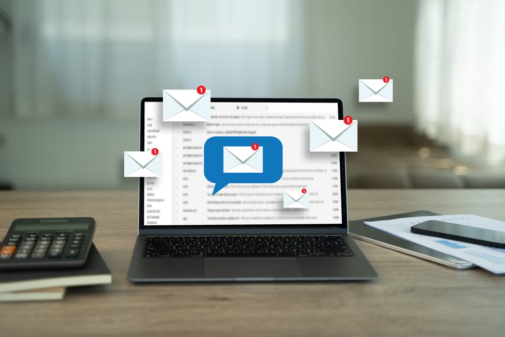 Overflowing email inbox on a laptop screen beside a cold cup of coffee