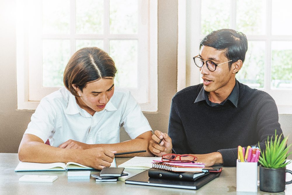 Teenager studying at a kitchen table with a phone timer running beside an open textbook