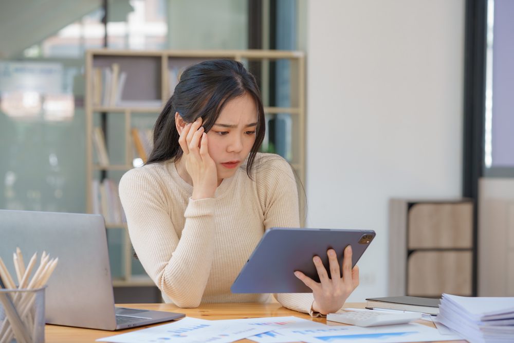 Woman removing her glasses and rubbing her eyes at a tidy desk after a long day