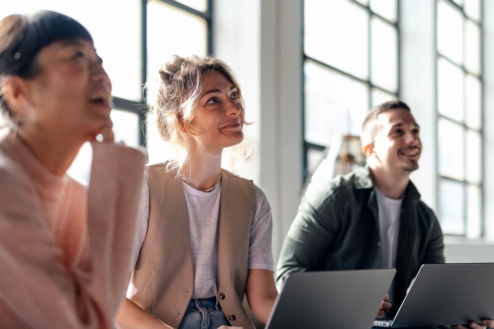 A group of people smiling and engaging in conversation during a meeting, symbolizing positive social interactions and connection in individuals with ADHD.