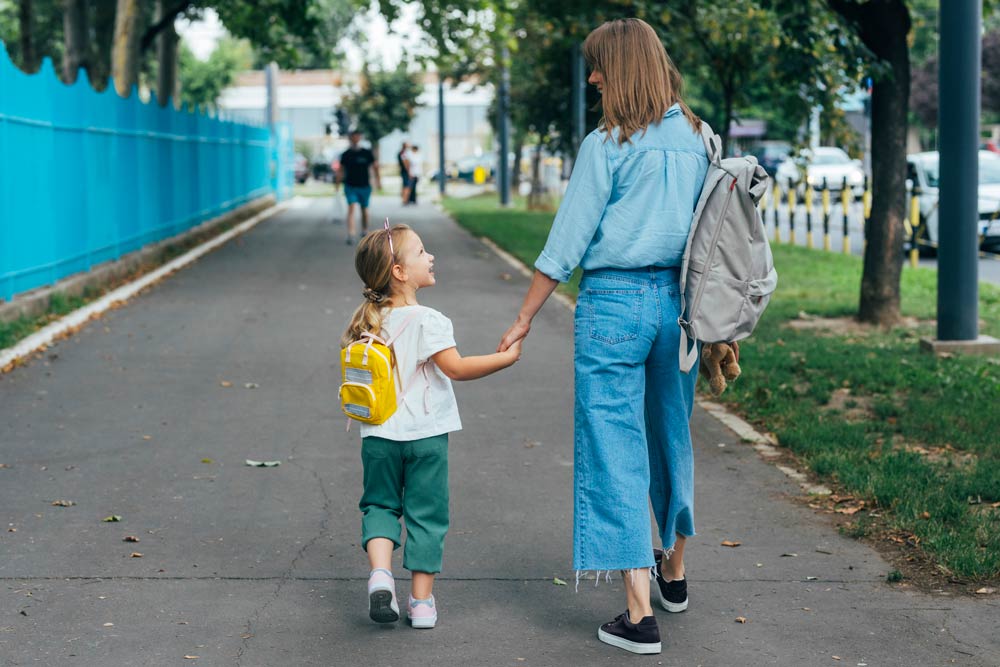 A mother walking her young daughter to school, symbolizing how ADHD symptoms can present differently in girls and women across life stages.