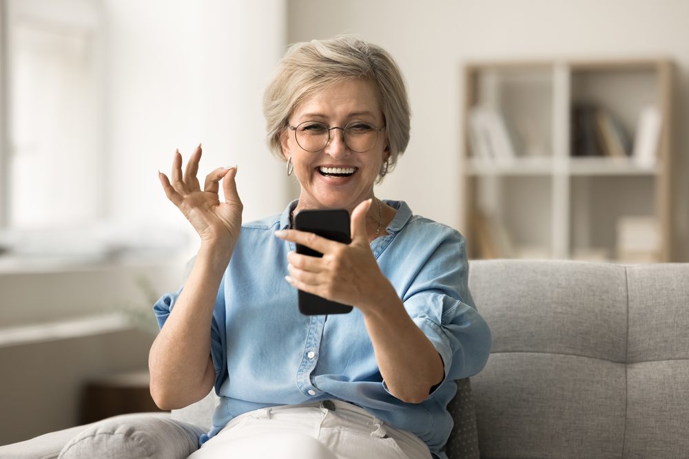 Woman on a video call at her kitchen table taking notes in a small notebook
