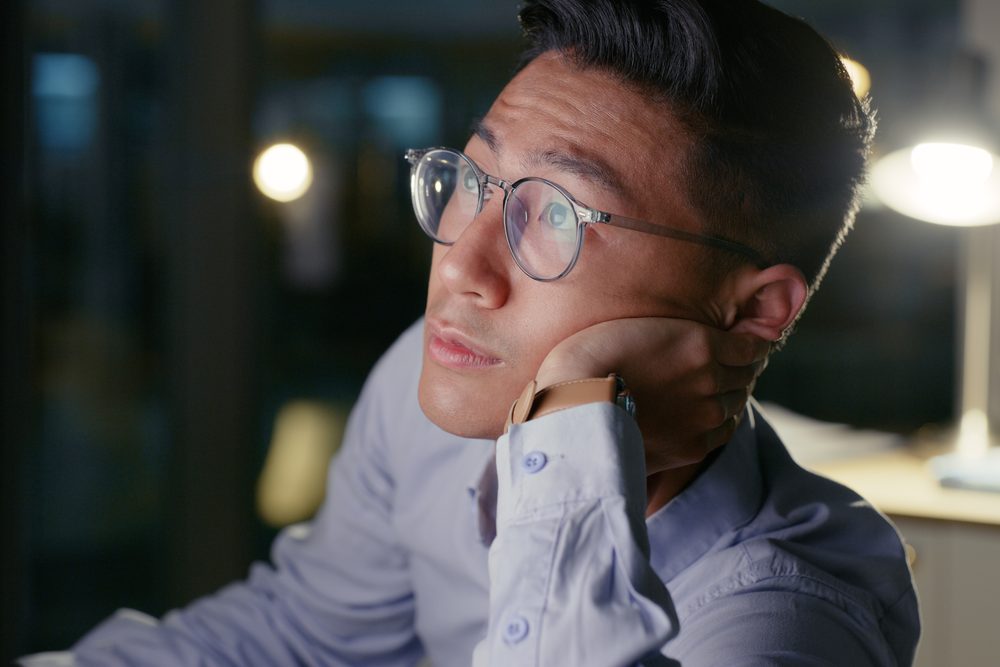 Person working at a laptop late at night with a wall clock showing eleven