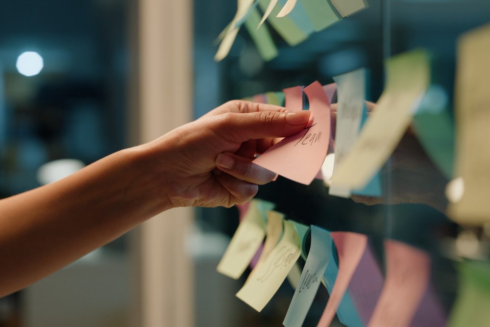 Sticky note with a short handwritten plan stuck to the edge of a laptop screen
