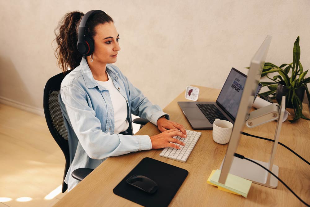 A student wearing headphones working at a computer, representing strategies for breaking large tasks into smaller, manageable steps for ADHD focus and productivity.