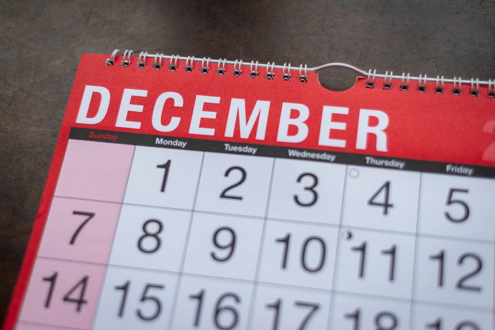 Wall calendar covered in coloured sticky notes above a student desk