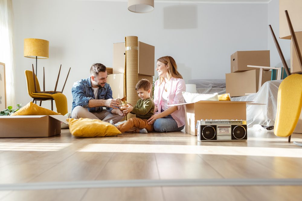 Young adult unpacking boxes in a bright, sparsely furnished apartment