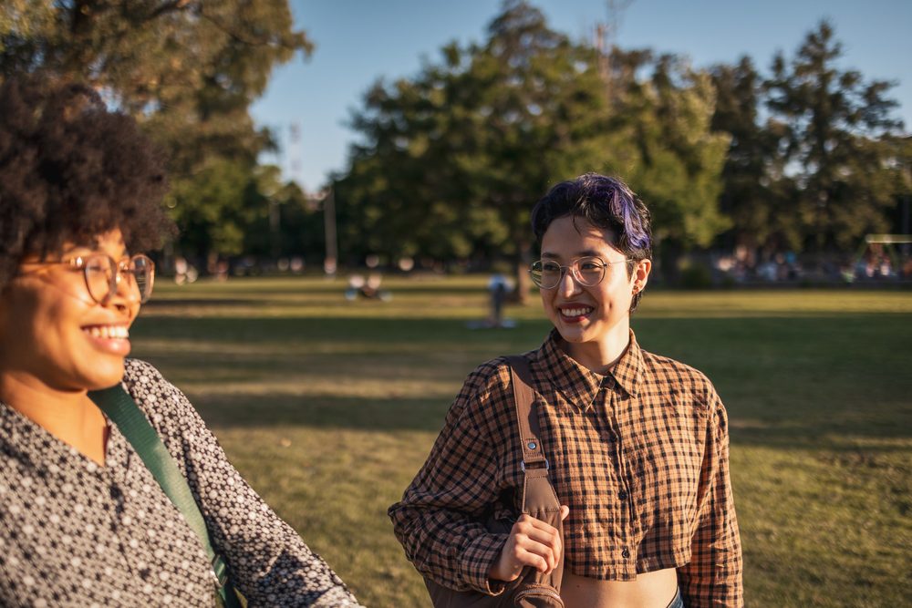 Two women on a park bench, one showing the other something on her phone