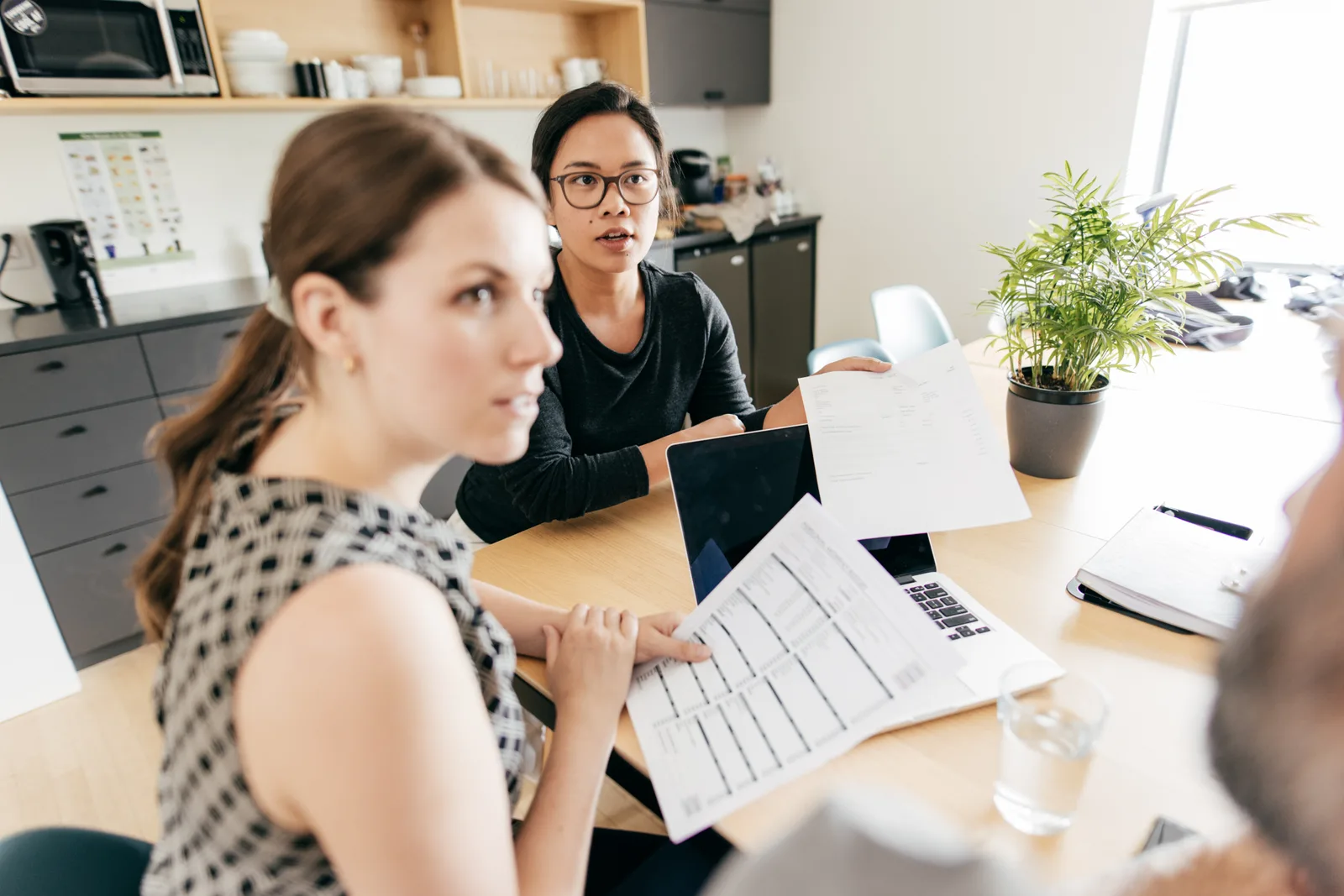 Couple at a kitchen table working through a household budget with a laptop and notebook, planning how to pay for an ADHD assessment.