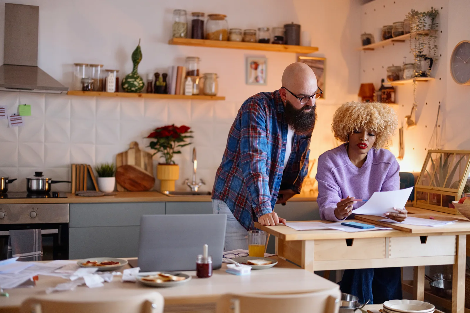 Canadian couple reviewing benefits paperwork and a laptop together at their kitchen table.