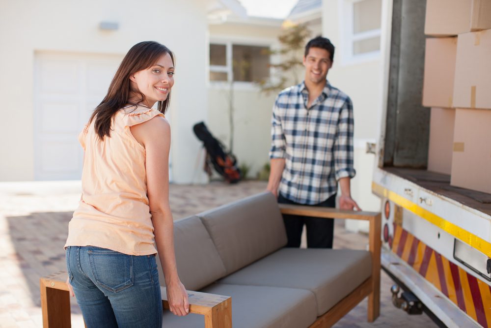 Couple at opposite ends of a sofa in the evening, one reaching a hand across