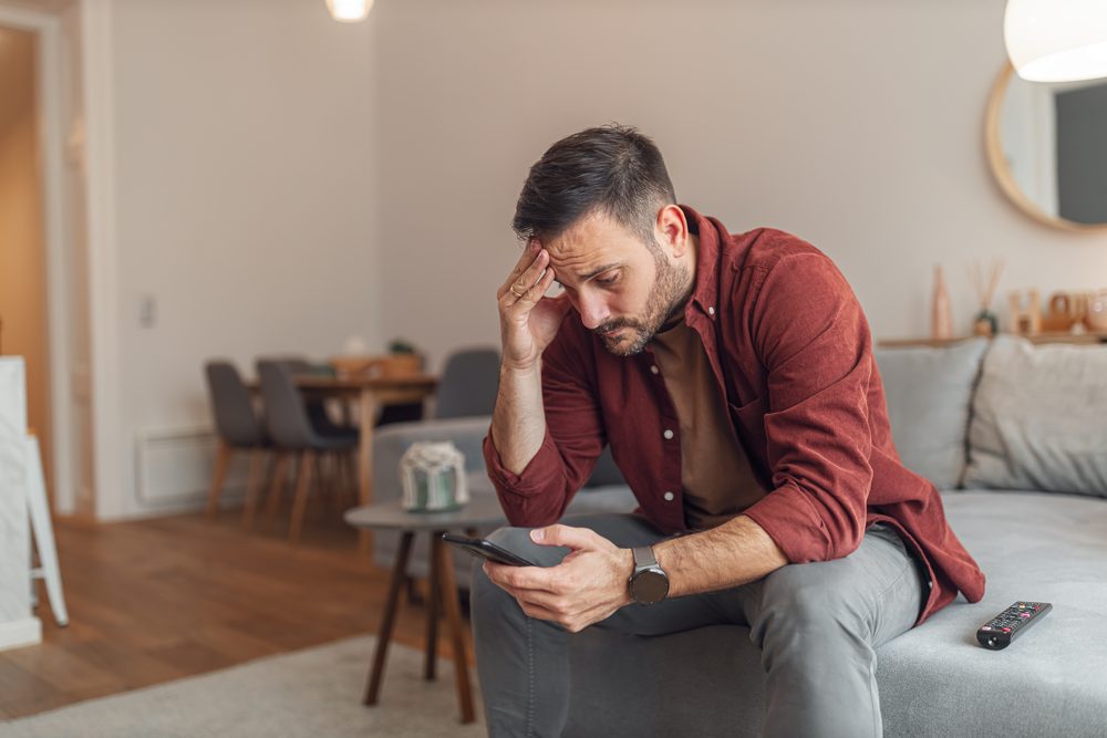 Person lying on a couch at night, face lit by a phone screen