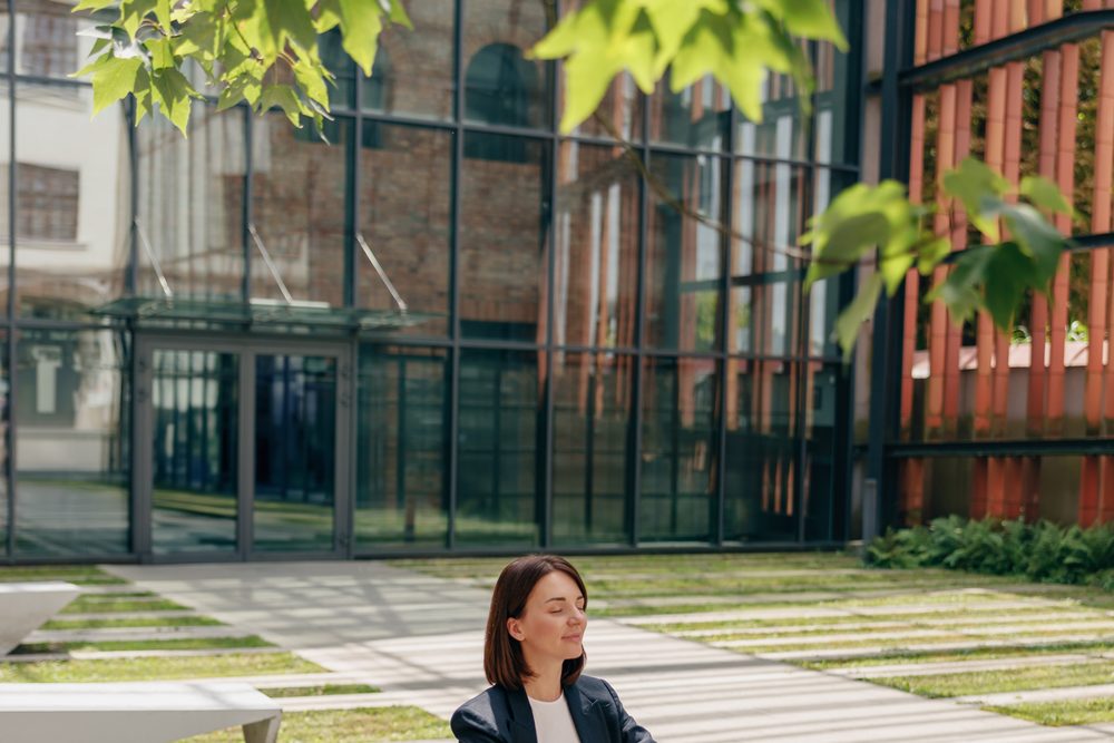 Woman sitting on a bench outdoors with her head in her hands, phone beside her