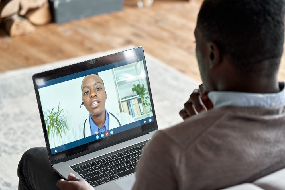 Woman working at a laptop with a video call window showing another person working