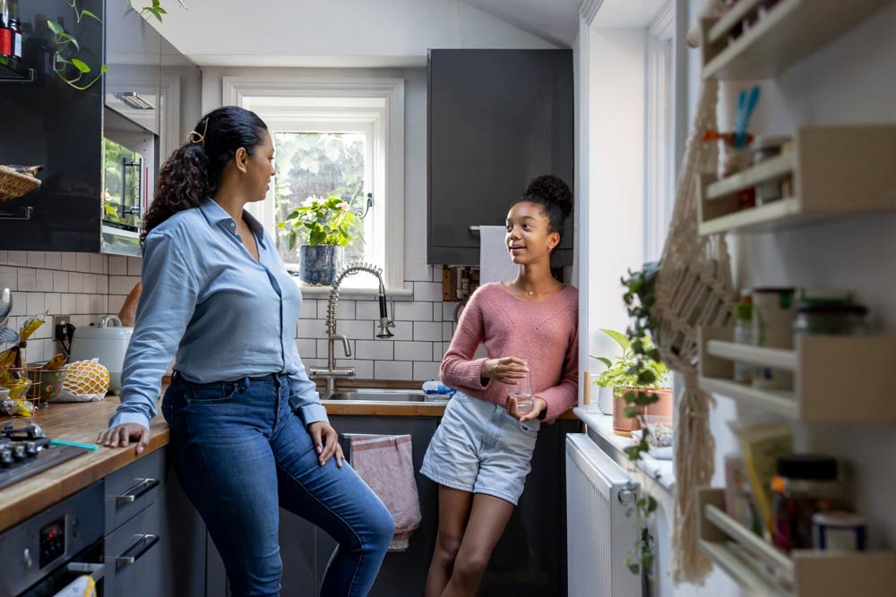 Mother and daughter having a supportive conversation in the kitchen about ADHD.