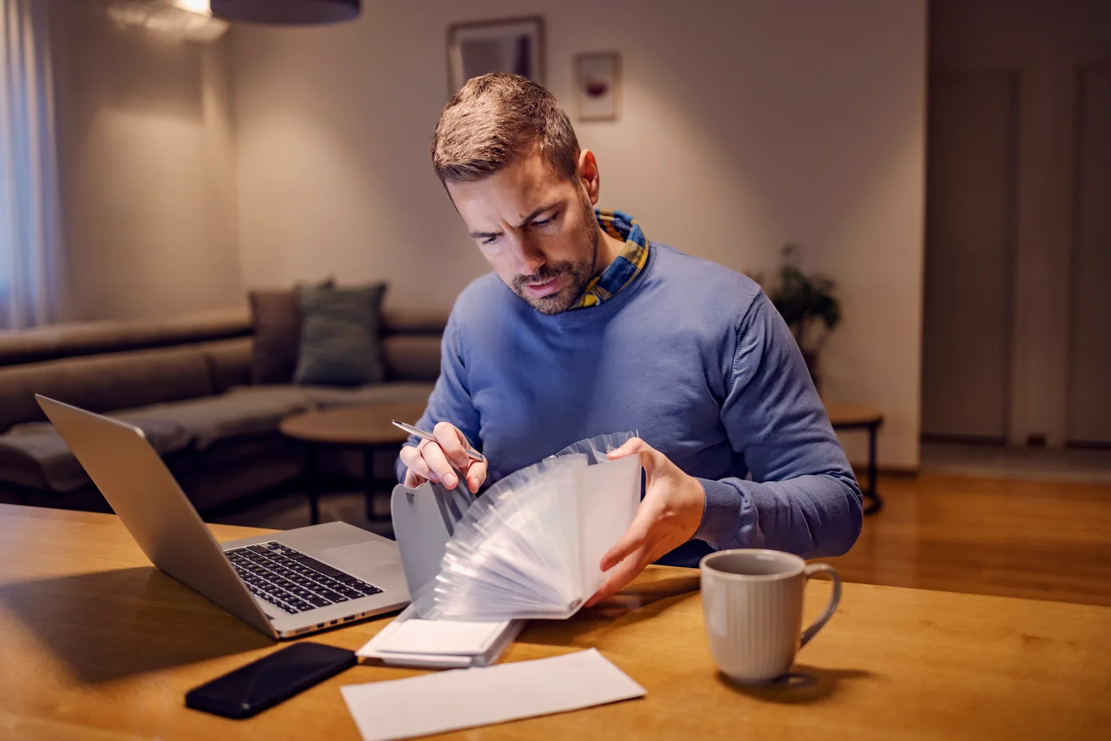 A man at his dining table organizing his assessment report and handwritten notes before an appointment with his family doctor.